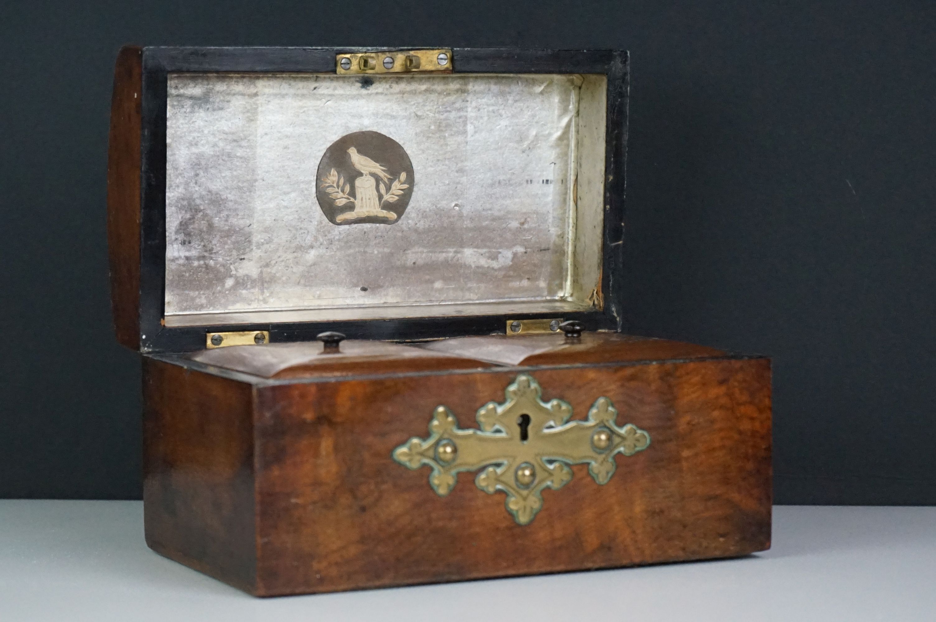 A wooden tea caddy in the form of a chest with brass pierced decoration.