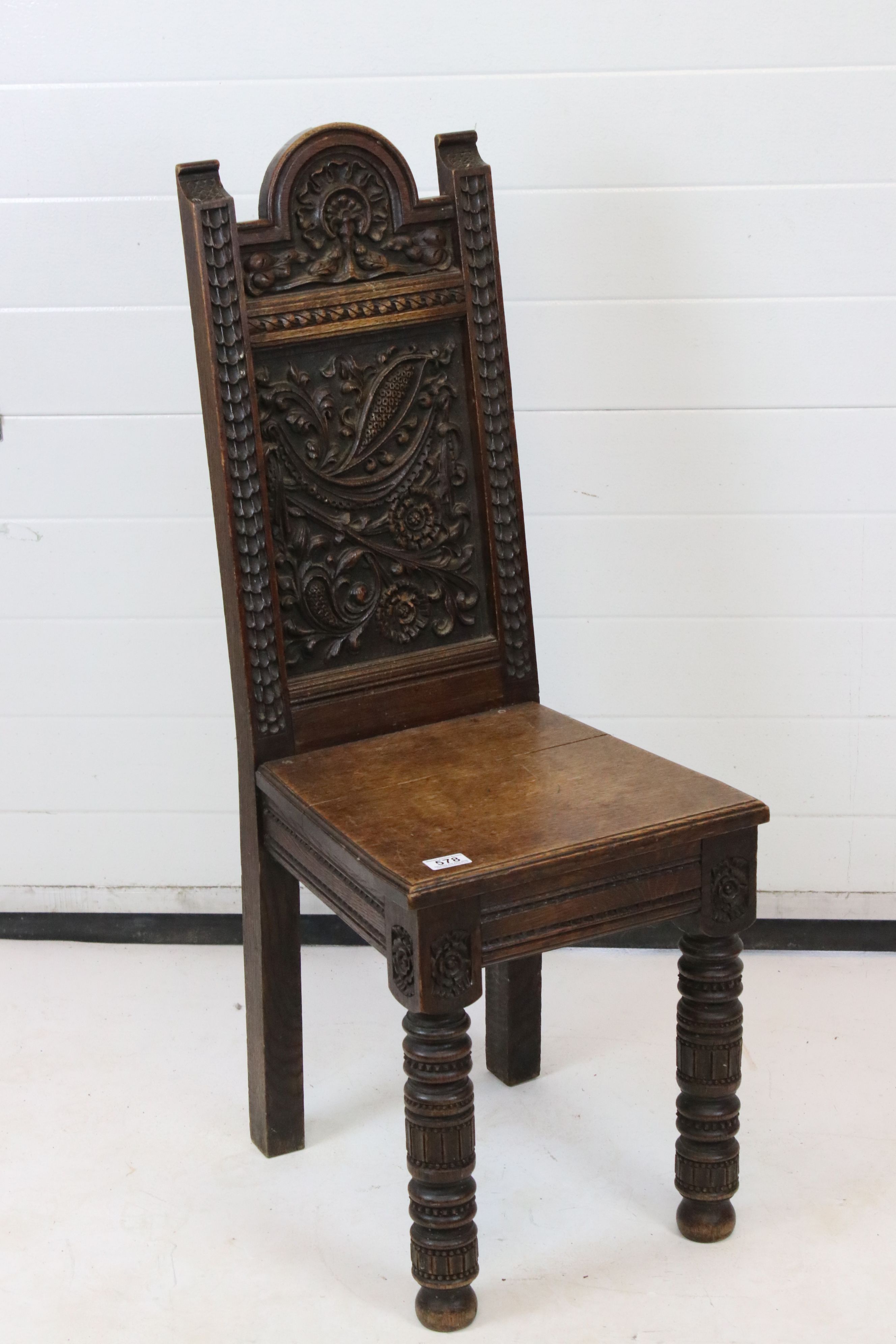 Victorian Jacobean Revival Oak Hall Chair, the arched rectangular back heavily carved with foliage