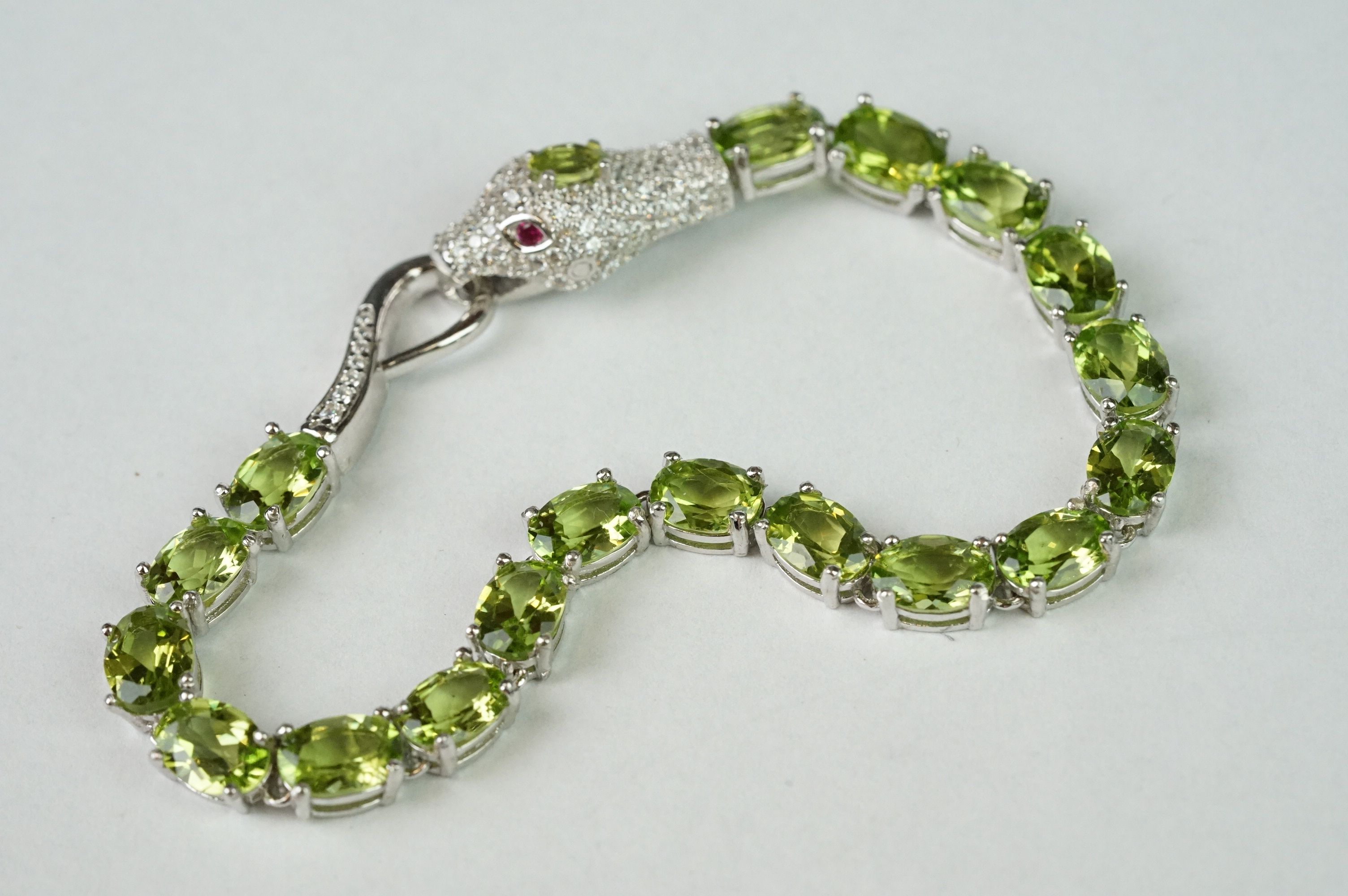 Silver CZ & peridot line bracelet, set with a snake head clasp set with ruby eyes