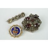 A collection of three brooches to include a George IV enamelled shilling coin brooch, yellow metal