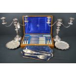 A small collection of silver plate to include a cased fish cutlery set and a pair of candelabras.