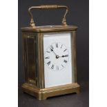 A vintage brass cased carriage clock with beveled glass panels and white enamel dial.