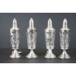 A set of four glass pepperettes with decorative white metal overlay.