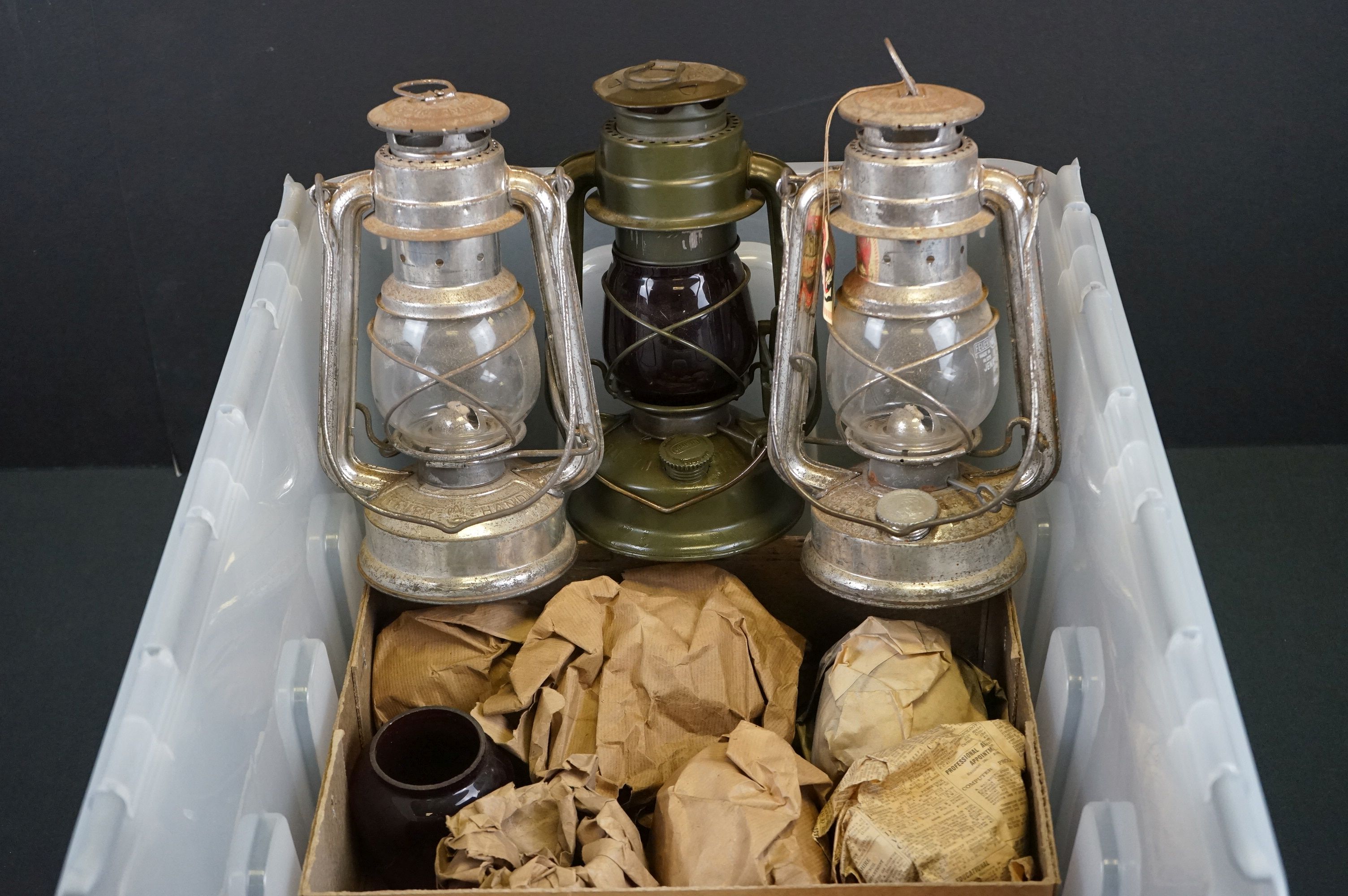 A Collection Of Three British Military Storm Lanterns Together With A Quantity Of Spares Glass