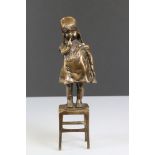 Bronze figure of a naughty child standing on a stool, approx. 28cm tall