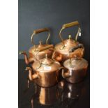 A collection of four antique copper kettle with brass fittings.