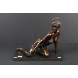 A large bronze figure of a scantily clad female on a polished granite stand.