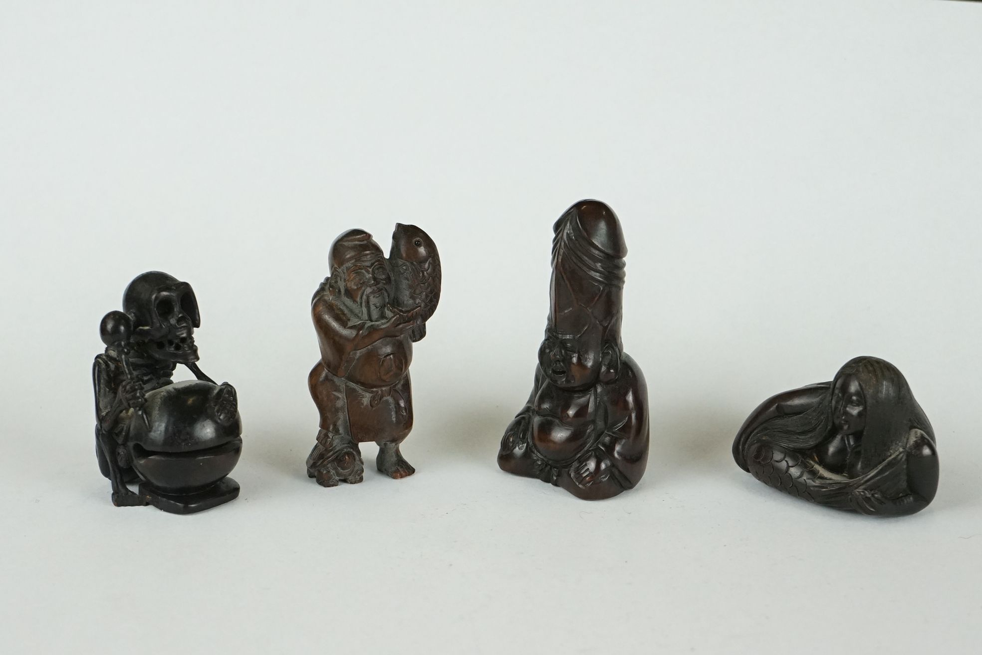 A collection of four Chinese carved wooden netsuke of figural form to include a Mermaid and a