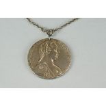 A silver necklace with a maria theresa thaler coin pendant.