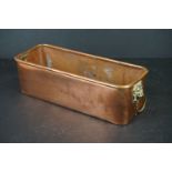 An antique copper planter with brass lion head handles.