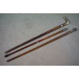 A collection of three walking canes to include two with white metal finials and one antler handle.