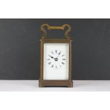 An antique brass cased carriage clock with white enamel dial.