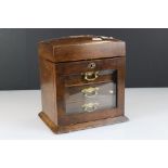 An antique wooden jewellery box with fitted interior, three drawers and bevelled glass drop door.