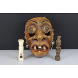 A carved wooden Sri Lankan face mask together with two carved figures.