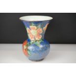 Royal Doulton trumpet shaped vase, with polychrome floral and leaf decoration on blue ground,