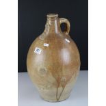A large primitive stoneware jug with decorative facial feature to the neck.
