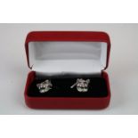 A pair of cat head silver cufflinks with ruby eyes.