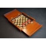 A mahogany cased travel chess set with red & white bone pieces.