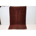 Eastern Red Ground Wool Bokhara Rug, the centre with two rows of nine Guls within a geometric