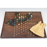 An early to mid 20th century wooden solitaire board together with marbles.