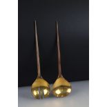 A pair of brass salad servers with wooden handles.