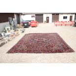 Large Wool Red Ground Rug decorated with geometric floral pattern within a border, 483cm x 417cm