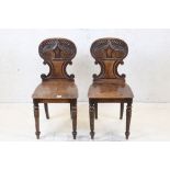 Pair of William IV Mahogany Hall Chairs, the shaped backs carved with leaves and scrolls, raised