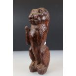 Black Forest style naive carved Lion sitting on his haunches with glass eyes, 33cm high