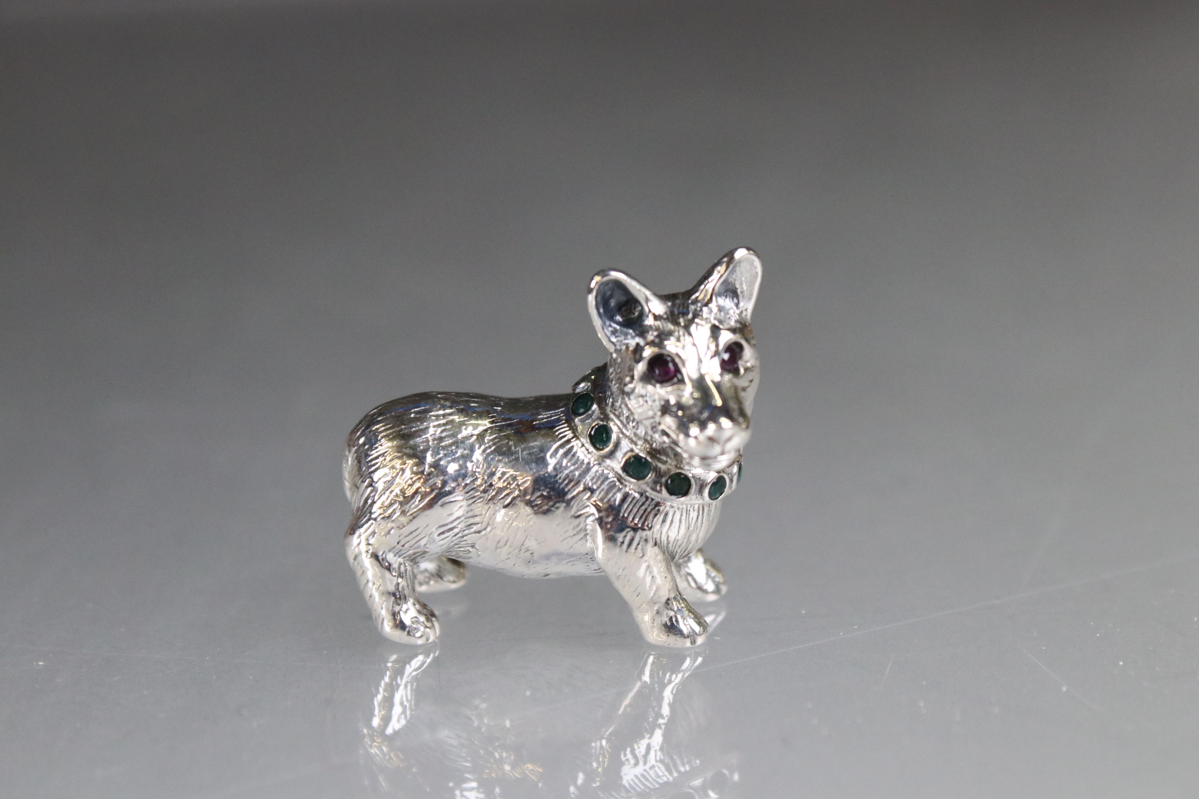 Silver figure of a dog with emerald collar