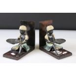 Pair of painted bronze bookends decorated with painted young Indian men in turbans, holding shells