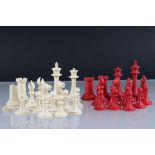 An antique carved bone red & white chess set in the style of Staunton.