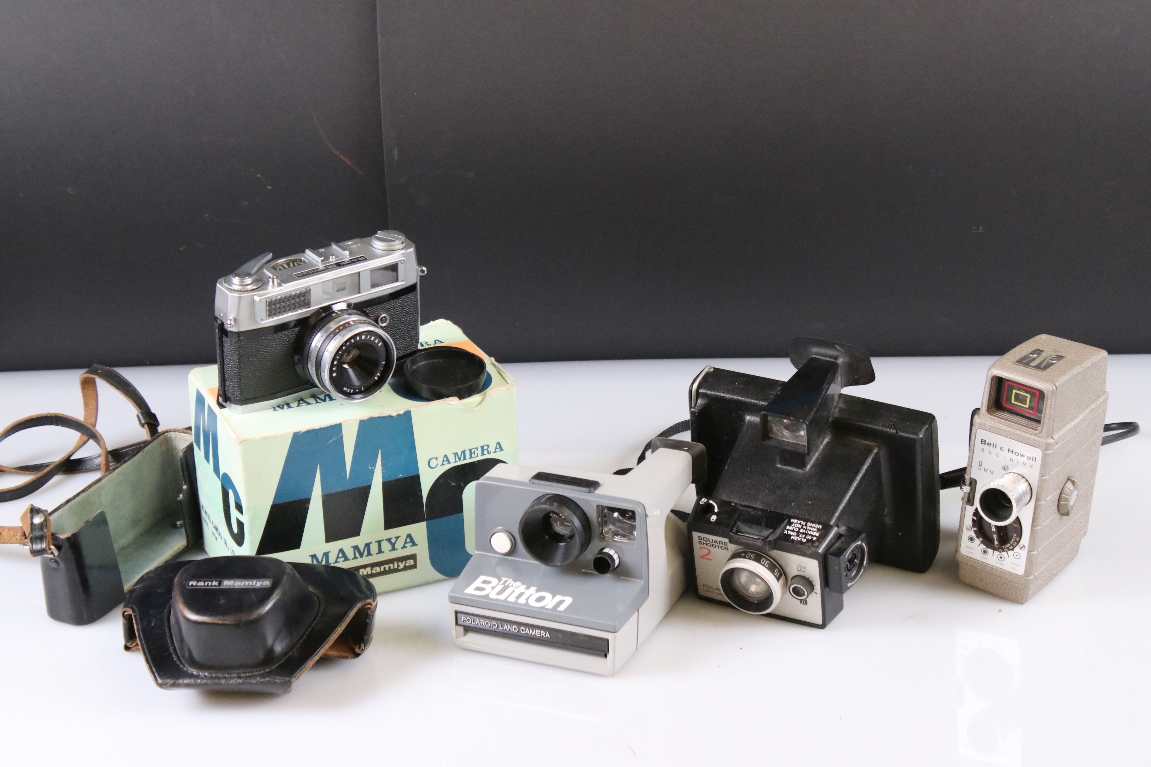 A small collection of vintage cameras to include Polaroid and Bell & Howell examples.