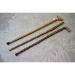 A collection of three walking sticks to include a hand carved example with pheasant handle marked