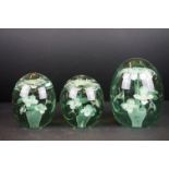 Three 19th Century green glass dump end of day paperweights, each inset with flowers, tallest approx