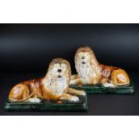 Pair of 19th century pottery Staffordshire type models of recumbent lions, on rectangular bases,