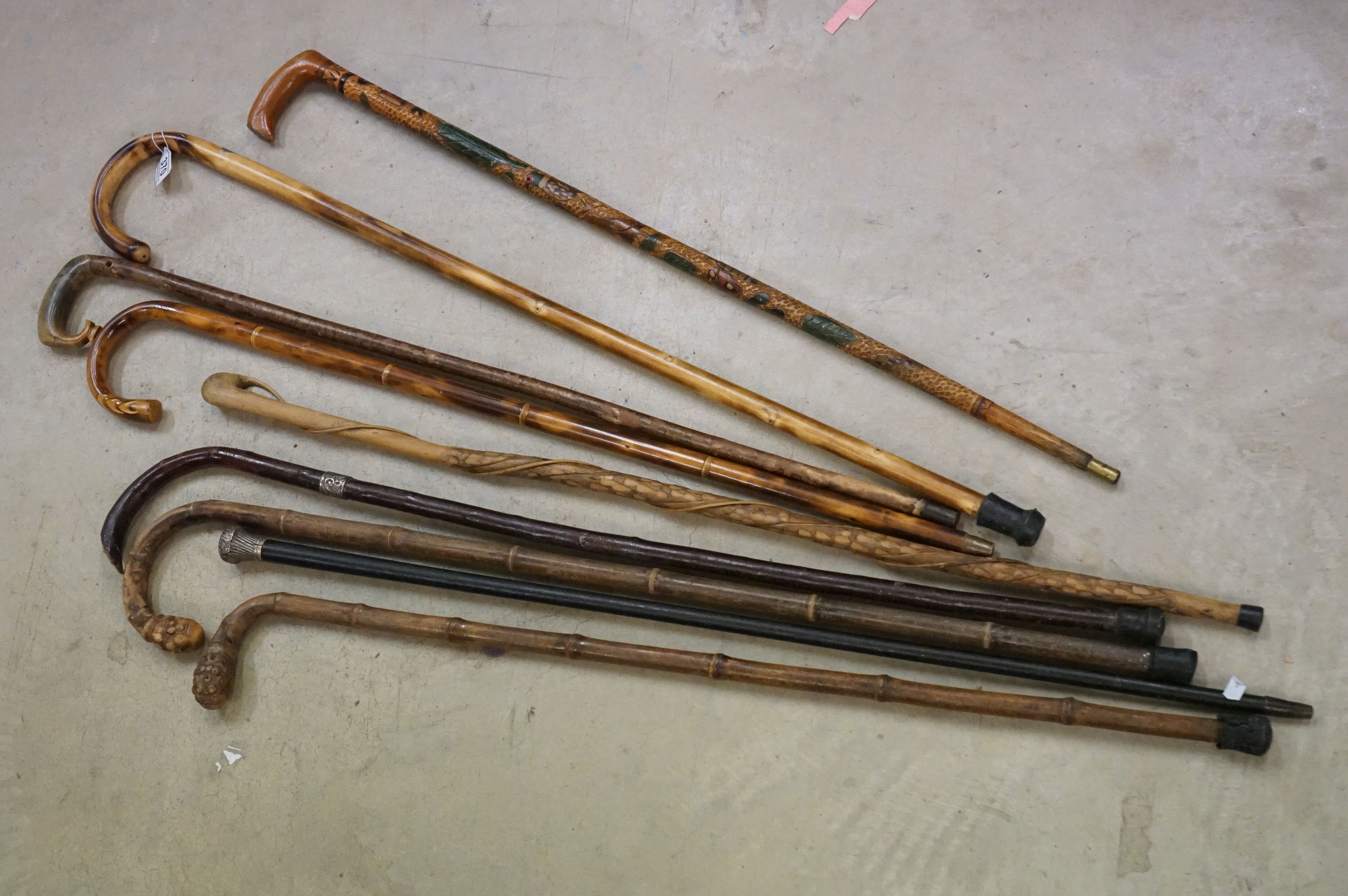 A collection of approx nine walking sticks to include a silver collard example.