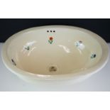 Terracotta Mexican sink of oval form with floral decoration on a pale yellow ground, approx 50cm