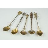 A collection of five white metal teaspoons to include four gilt examples with ornate finials.