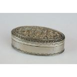 White metal oval vinaigrette, the hinged lid with repousse floral decoration, the body with engraved
