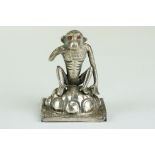 Continental white metal figurine modelled as a squatting monkey, red glass eyes, height approx 3.5cm