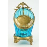 Late 19th century blue glass and brass pocket watch display case, raised on four cast feet, rose bud