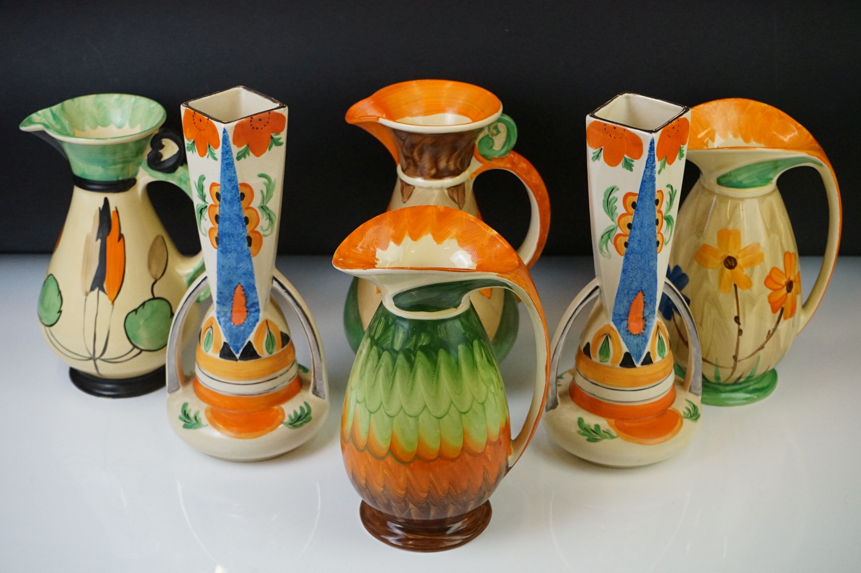 Four Myott, Son & Co hand painted Art Deco footed jugs, decorated with colourful floral, foliate and