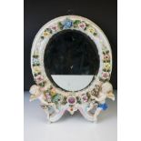 Dresden porcelain dressing table mirror of oval form, with bevel glass surmounted by two cherubs