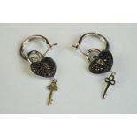 A pair of silver and CZ heart shaped drop earrings, heart and key