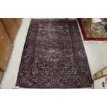 Maroon Ground Wool Rug decorated with a stylised floral design within a border, 185cm x 125cm