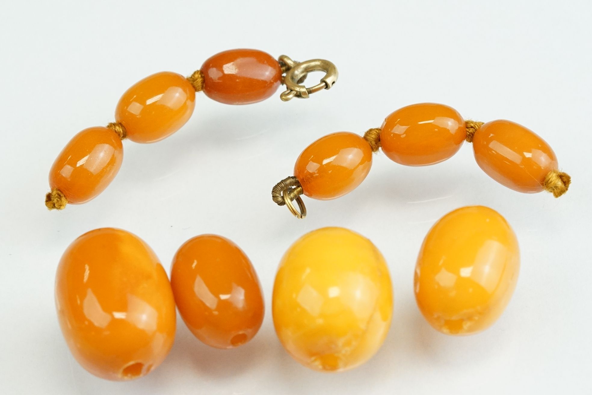 Ten amber type beads, the largest measuring approx 20mm x 14mmm, the smallest measuring approx 10.