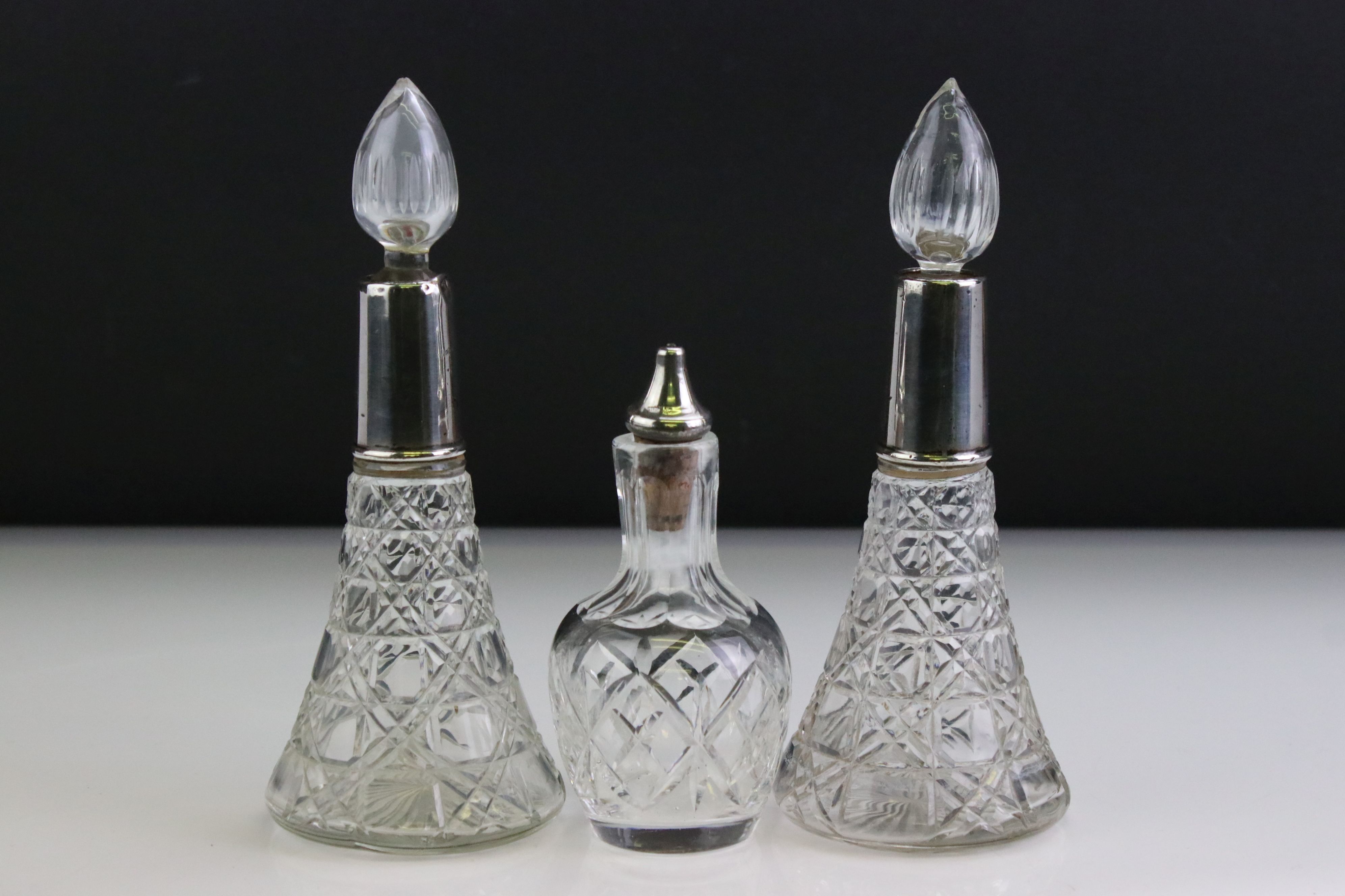 Pair of George V silver collared conical cut glass scent bottles with star-cut bases, with flame-