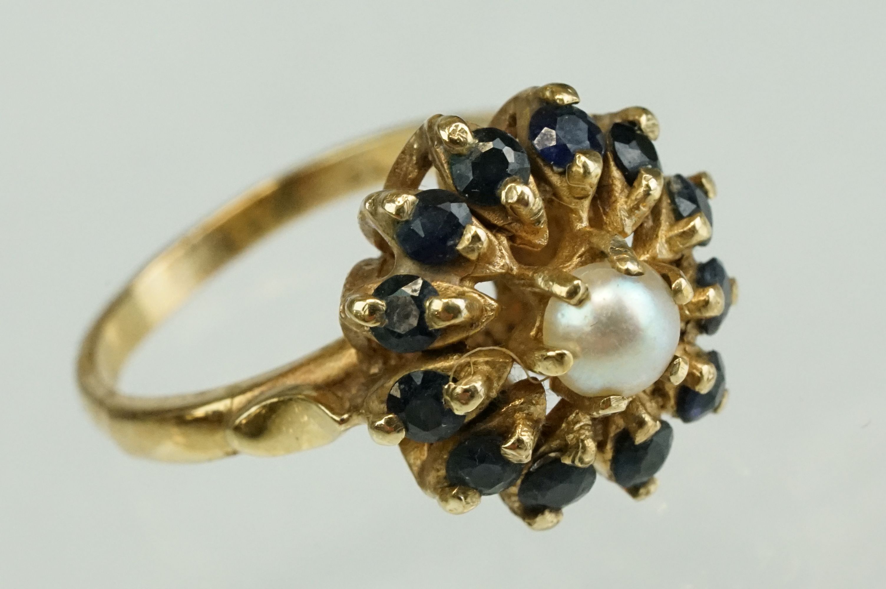 Pearl and sapphire 9ct yellow gold flower head cluster ring, the white cultured pearl to centre with