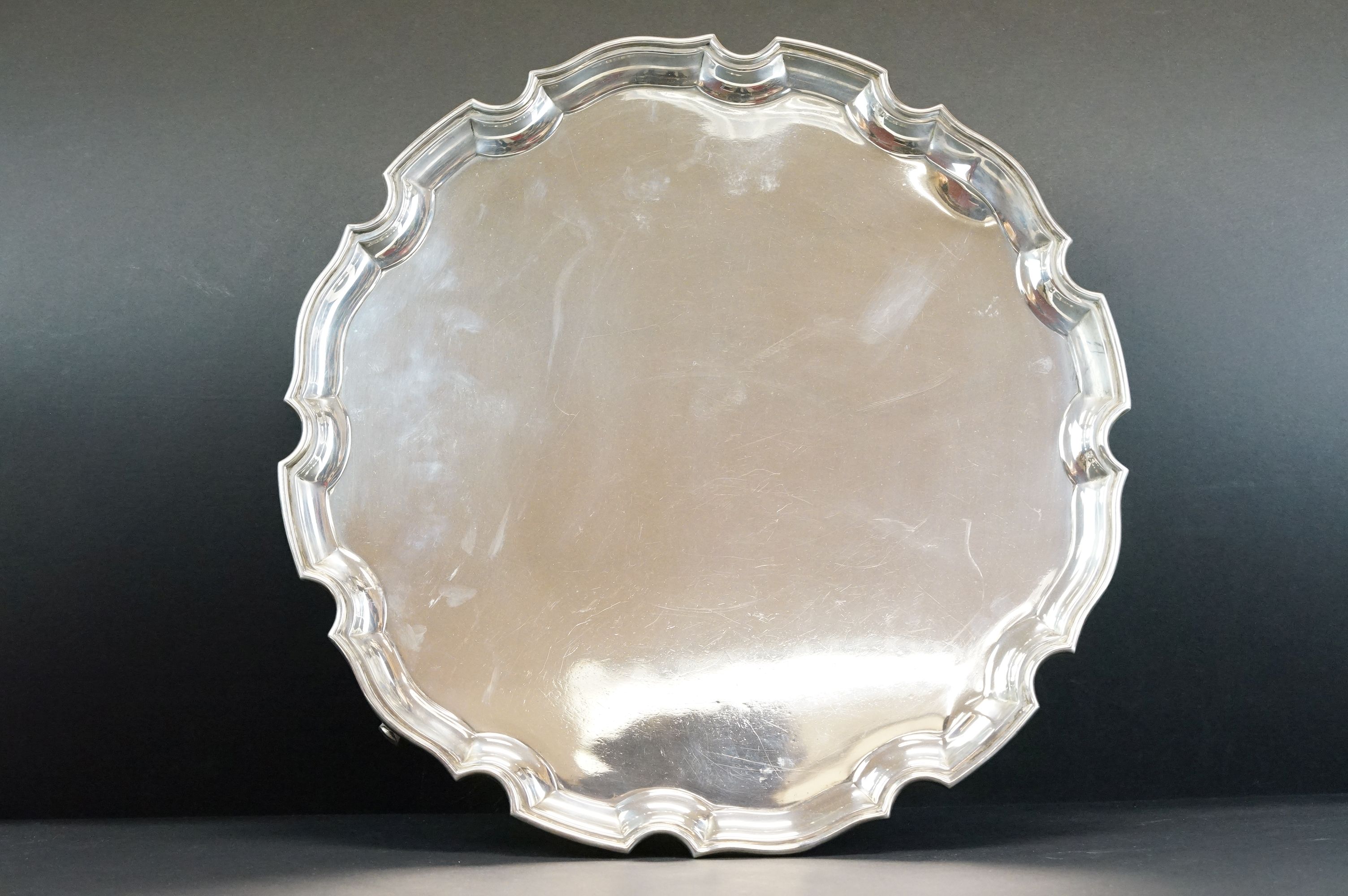 Silver salver raised on four scroll feet, plain polished, Chippendale style border, makers Adie