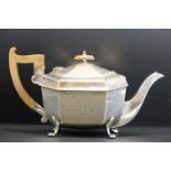 Silver teapot, wooden handle and finial, the octagonal body raised on four feet, engraved military